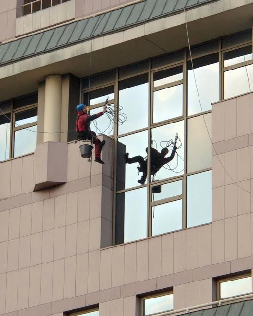 A man cleaning a glass window with a mop in grayscale, showcasing professional work.