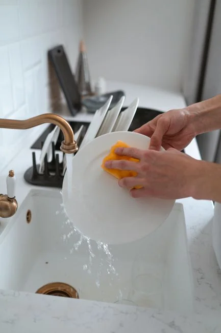 A man cleaning a glass door indoors using a spray bottle and cloth.